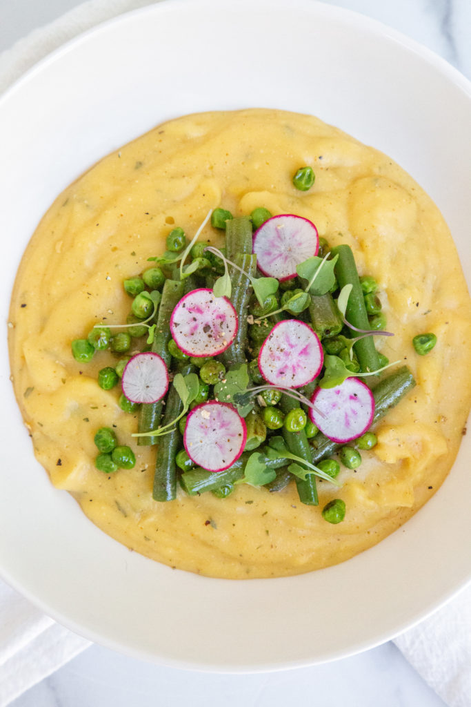 creamy vegetable polenta with green beans, radish, and sprouts