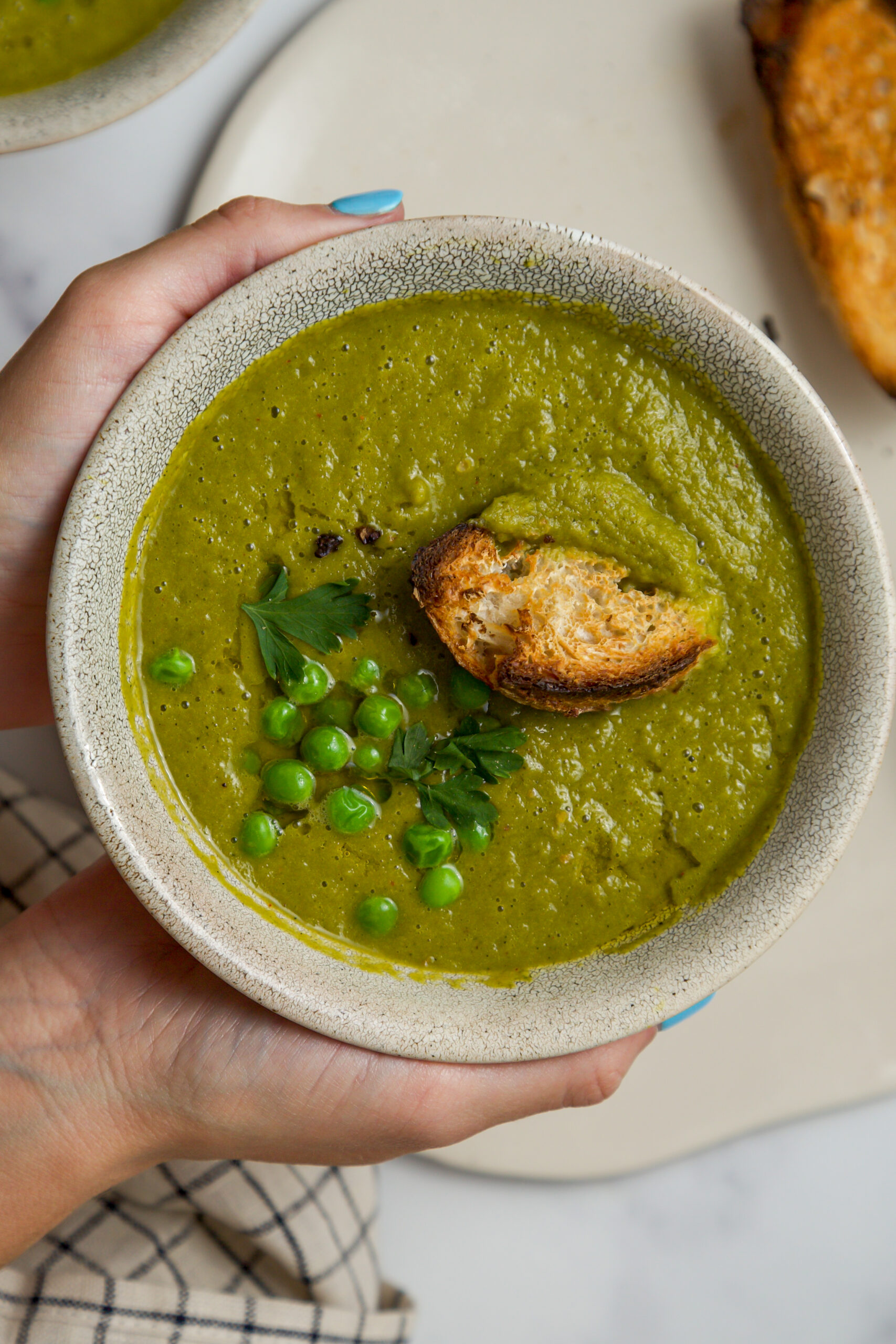 hands holding green soup with peas