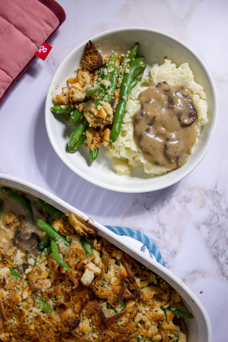 Plate of fresh vegan green bean casserole and mashed potatoes with mushroom gravy.