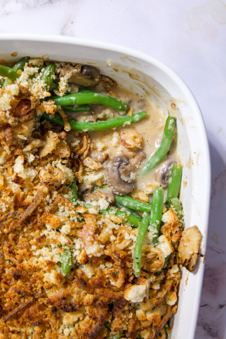 Close-up of fresh green bean casserole with mushrooms and golden breadcrumb-onion crust.