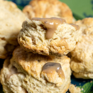 Close-up of flaky sourdough discard biscuits with creamy vegan mushroom gravy dripping over the top