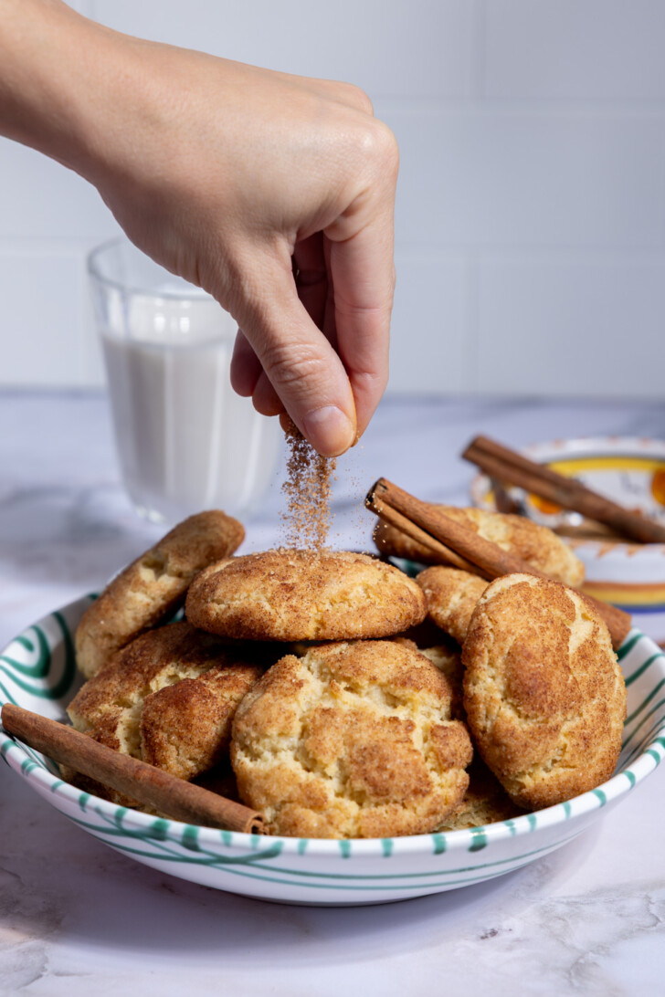 Sprinkling cinnamon sugar over freshly baked vegan snickerdoodles
