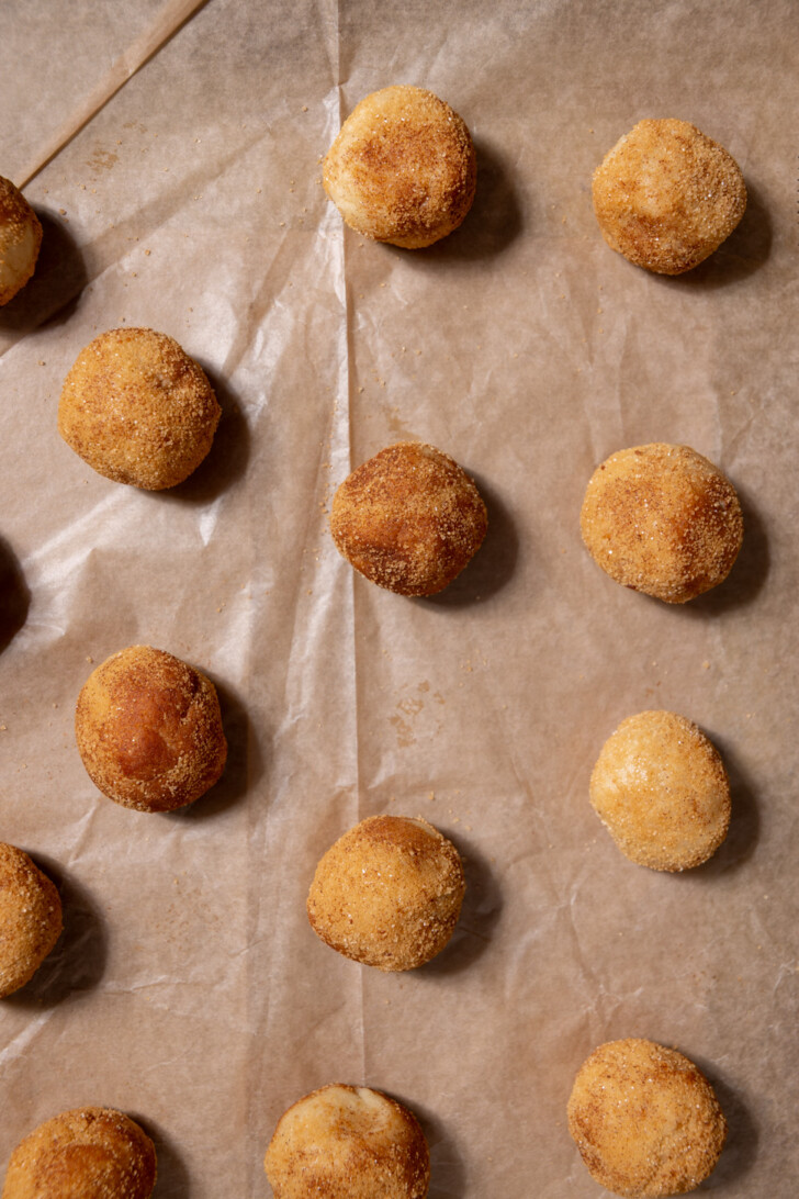 Vegan snickerdoodle dough balls rolled in cinnamon sugar before baking